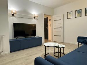 un salon avec un canapé bleu et une télévision dans l'établissement Apartamenty Planeta - 12 Koszalin, à Koszalin