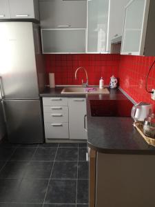 a kitchen with white cabinets and red tiles at Emilka in Suwałki