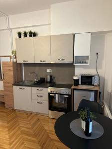 a kitchen with white cabinets and a table with a bottle of wine at Cozy Faliro home in Piraeus