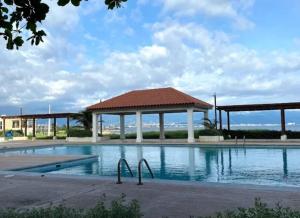 uma piscina com um gazebo e o oceano em Balcony Sea Breeze @ Bayfront Villas Portmore em Portmore