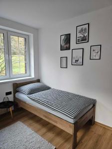 Horský apartmán MIKI في Filipovice: سرير في غرفة بيضاء مع صور على الحائط