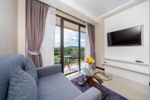 a living room with a blue couch and a television at Mountain View Mai Khao Beach Condotel in Ban Bo Sai Klang
