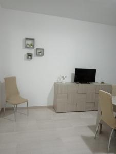 un salon avec des chaises et une télévision sur un meuble dans l'établissement Casa Vacanza Luna2, à Palagiano