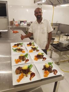 Un uomo in piedi davanti a un tavolo di cibo di Eighth Wonder Resort a Sigiriya
