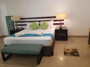a bedroom with a large bed and a green stool at Eighth Wonder Resort in Sigiriya