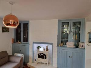 Lily Cottage In Idyllic Reedham في Reedham: غرفة معيشة بها دواليب زرقاء وحوض أسماك