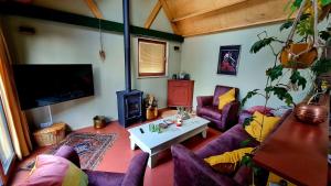 a living room with purple furniture and a tv at Wellness op'e Klaai in Holwerd