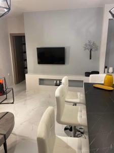 ein Wohnzimmer mit weißen Stühlen und einem TV an der Wand in der Unterkunft Modern house in Stratoni in Stratoni