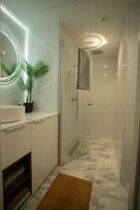 ein weißes Bad mit einer Dusche und einem Waschbecken in der Unterkunft Tatari 16 City Centre New Apartment in Tallinn