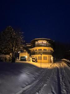una gran casa amarilla en la nieve por la noche en SONNENLODGE St Anton am Arlberg, en Sankt Anton am Arlberg