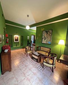 ein Wohnzimmer mit grünen Wänden sowie einem Tisch und Stühlen in der Unterkunft La Stazione di Posta in Cassino