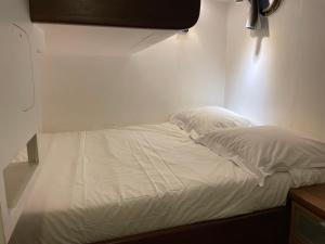 un letto con lenzuola e cuscini bianchi in una stanza di Cabine sur péniche à Bagatelle a Parigi