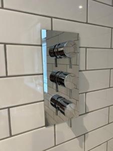 a tiled wall with two water knobs on it at Brand New Cosy 1 Bedroom Home in Nantwich