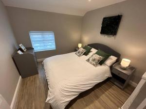 een slaapkamer met een wit bed met kussens en een raam bij Brand New Cosy 1 Bedroom Home in Nantwich