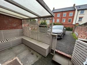 uma pérgola de madeira com um carro estacionado num parque de estacionamento em Brand New Cosy 1 Bedroom Home em Nantwich