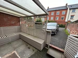 a wooden pergola with a car parked in a parking lot at Brand New Cosy 1 Bedroom Home in Nantwich