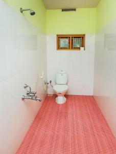 a bathroom with a toilet and a red rug at Urban Rose Homestay in Kannur