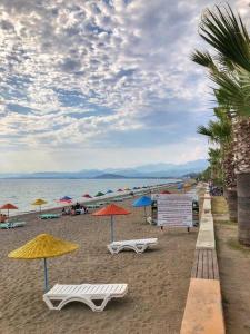 a beach with chairs and umbrellas on the sand at GENI Apartment - Center Of Fethiye Close to the Beach Fast Wi-Fi Netflix in Fethiye