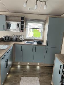 a kitchen with white cabinets and a sink and a window at Sun sea and sand at Whitley bay caravan park in Whitley Bay