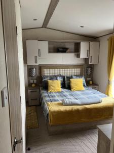 a bedroom with a large bed with yellow pillows at Sun sea and sand at Whitley bay caravan park in Whitley Bay