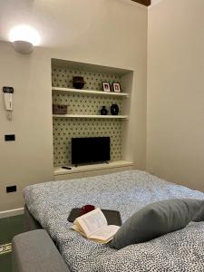 Schlafzimmer mit einem Bett mit einem Buch und einem TV in der Unterkunft Casa Giulietta in Cremona