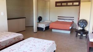 a bedroom with two beds and a table and a chair at Pousada e Pizzaria Sol e Alegria in Fortaleza