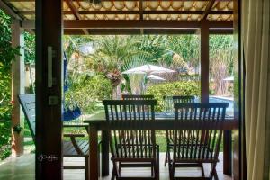 Linda Casa no Pipa Beleza في بيبا: طاولة مع كراسي ومظلة على الفناء