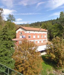 a large brick building in the middle of trees at L'Ancienne Colonie - maison conviviale au bord de la Gazeille - 8 pers in Le Monastier sur Gazeille