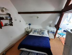 een slaapkamer met een bed met blauwe lakens en een raam bij Les Petits Matins Bleus - Chambres d'hôtes "Les Pommiers" in Sainte-Marguerite-de-Viette