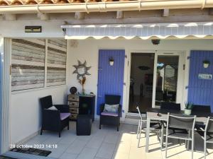 een patio met stoelen en een tafel in een gebouw bij Villa tout confort dans résidence privée avec piscine à 500m de la plage - Climatisation, WIFI, parking in Portiragnes