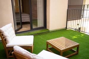 einen Balkon mit grünem Gras, 2 Stühlen und einem Tisch in der Unterkunft Apartamento NUEVO en el centro de LEON in León