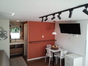 a dining room with a table with chairs and a tv at Pousada Ilha do Campeche in Florianópolis