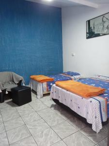 twee bedden in een kamer met een blauwe muur bij El Viajero Hostel & Suítes 10 in Pedro Juan Caballero