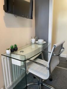 a glass desk with a chair and a tv at Ensuite Room, Hotel Standard. Close to Crewe Train Station in Crewe