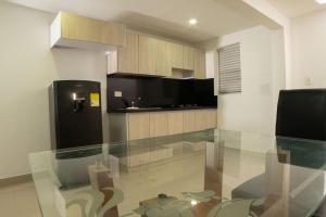 a kitchen with a glass table and a black refrigerator at Casa Hotel Jardín Plaza in Santa Marta