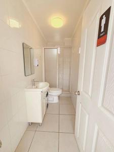 Baño blanco con aseo y lavamanos en Alojamiento Privado 403 en Antofa, en Antofagasta