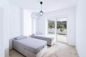 two beds in a white room with a window at Nikkon summer house in Matala