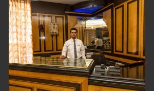 a man in a tie standing behind a glass counter at Hotel Sri Ram Residency in Udupi
