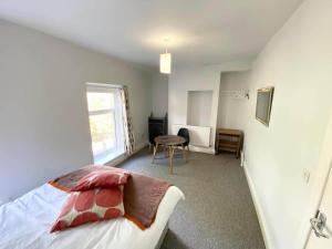 a bedroom with a bed and a table and a window at Budget Room Share facilities R3 in Swansea