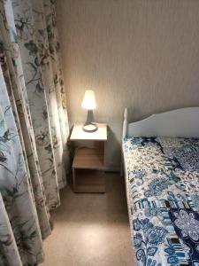 1 dormitorio con 1 cama y 1 lámpara en una mesa en Siisti valoisa kolmio, en Lieksa