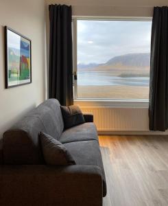 a living room with a couch and a large window at Hafnir in Grundarfjordur