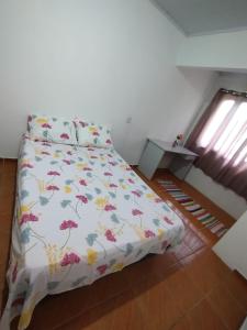 una camera da letto con un letto con copriletto floreale di POUSADA DA PONTE IBIRAQUERA a Imbituba