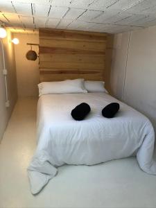 a large white bed with two black pillows on it at Casa Luz in El Pozo de los Frailes