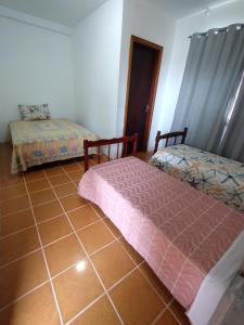 a bedroom with two beds and a tiled floor at POUSADA DA PONTE IBIRAQUERA in Imbituba