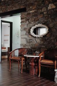 Habitación con mesa, sillas y pared de piedra. en Πέτρινο αρχοντικό, 