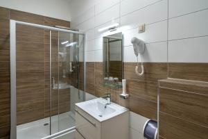 a bathroom with a sink and a shower and a phone at Inter Hotel in Debrecen