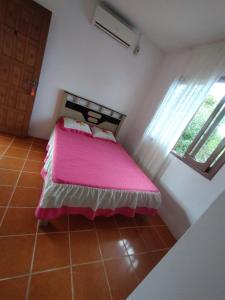 1 dormitorio con cama con sábanas rosas y ventana en POUSADA DA PONTE IBIRAQUERA, en Imbituba