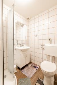 a white bathroom with a toilet and a sink at Dió Vendégház in Mezőkövesd
