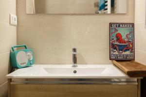 a bathroom sink with a mirror and a sign at Les Magnolias in Oullins