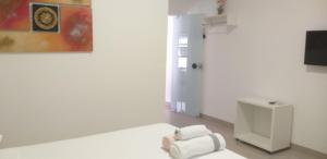 une chambre blanche avec des serviettes et un tableau sur le mur dans l'établissement Apartamento no centro próximo a Jk, à Palmas